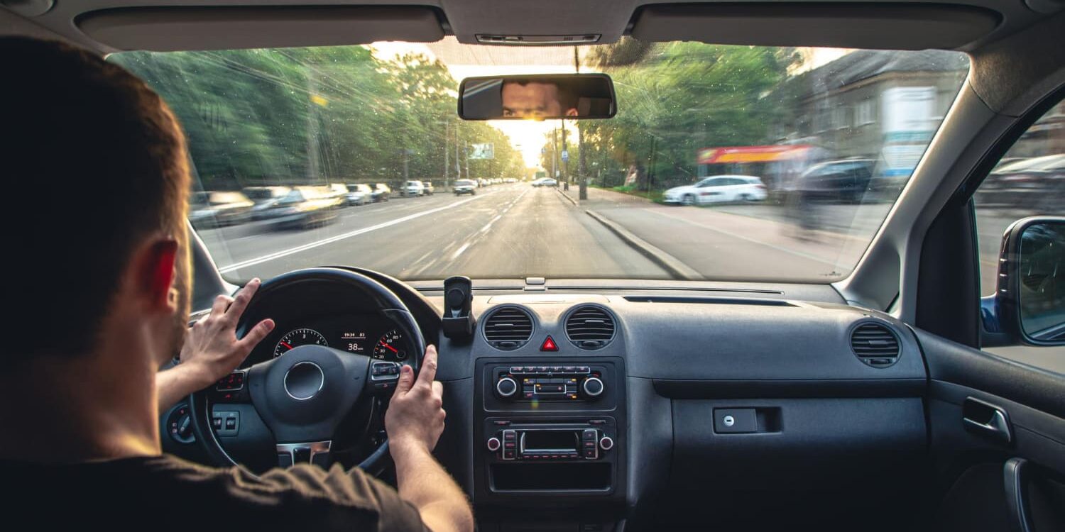 Auto rijden oefenen behalen theorie Man oefent veilig autorijden op rechte weg als onderdeel van autotheorie leren