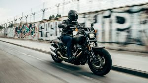 Motorrijder in zwarte outfit rijdt op een Harley-Davidson tijdens eerste dag motorrijles in stedelijke omgeving